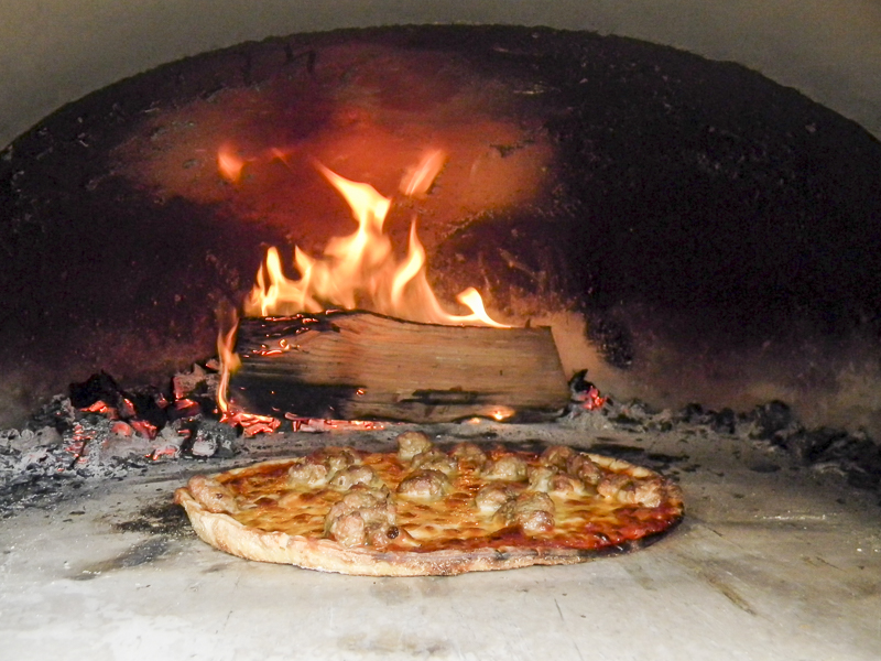 pizza cooked in outdoor brick oven